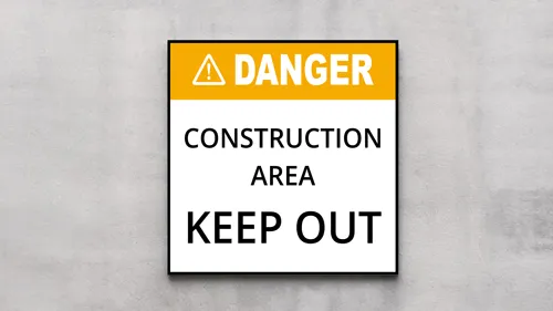 Plastic sign reading Danger Construction Area Keep Out to warn of hazardous site access.