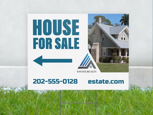 A yard sign for Estate Realty with a left arrow, a phone number, and a website.