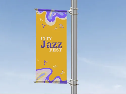 ​A vertical pole banner promoting a city jazz festival, featuring vibrant graphics and bold typography, mounted on a street pole in an urban setting