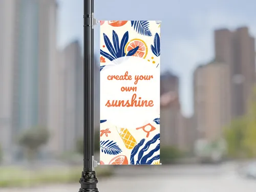 ​A single vertical pole banner featuring a colorful motivational quote design, mounted on a street pole in an urban environment
