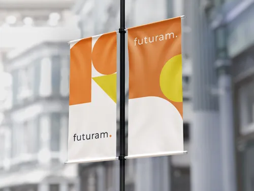 ​A single vertical pole banner with an orange and yellow marketing-themed design, mounted on a street pole in an urban environment