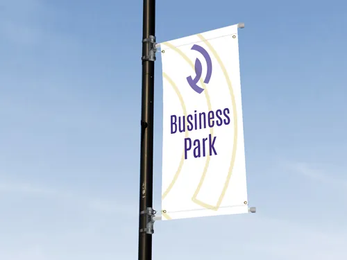 ​A single vertical pole banner with a purple design promoting a business park, mounted on a street pole in an urban environment