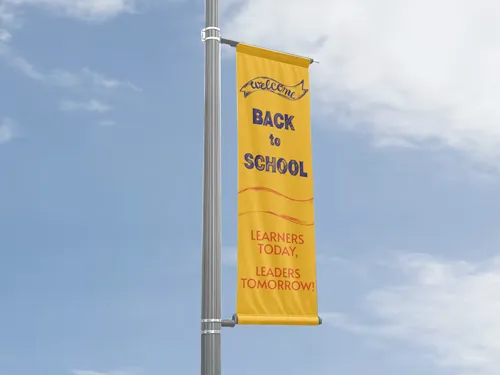 ​A single vertical pole banner with a yellow Back to School design, mounted on a street pole in an urban environment