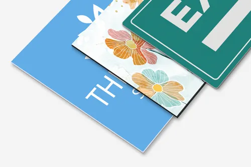 Stacked PVC signs showcasing a variety of designs, including floral art, an exit symbol, and a light blue thank-you message, highlighting versatility in signage styles