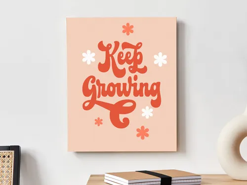 Decorative wooden sign with Keep Growing in white and orange, accented by tiny flowers.