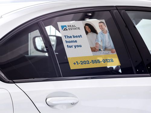 Perforated window decal on car door advertising real estate services with contact number.