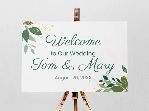 Elegant foam board sign with green botanical accents, displaying a wedding welcome message for Tom & Mary, mounted on a wooden easel